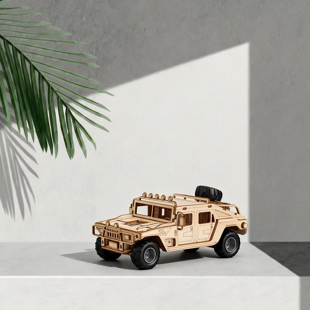 Wooden model of a military vehicle on a light surface with a palm leaf in the corner.